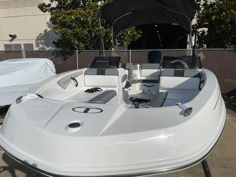 Slide: The Image of 2024 Tahoe T21 boat with black canopy and white seating, docked outdoors. - 9