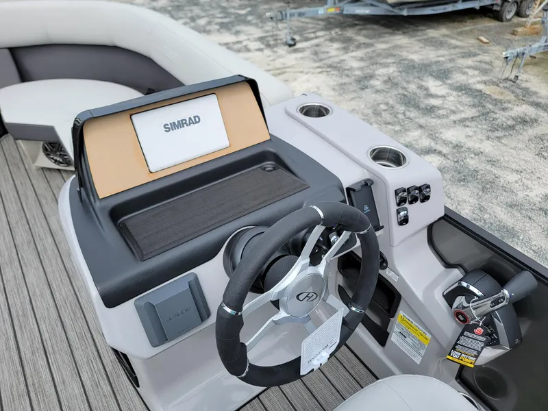 Slide: The Image of 2024 Harris Cruiser 210 boat dashboard with Simrad display and steering wheel. - 15