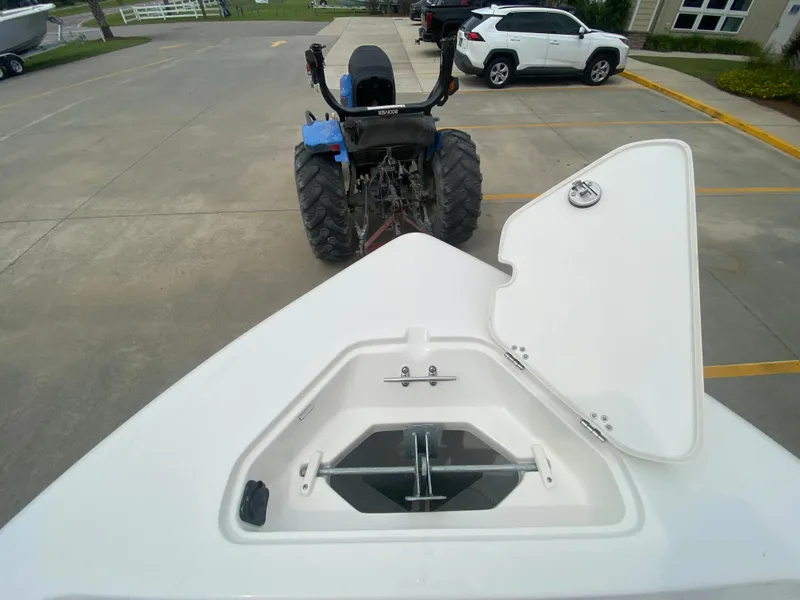 Slide: The Image of 2024 Key West 189 FS boat anchor compartment with open lid, parked near a tractor and white SUV. - 20