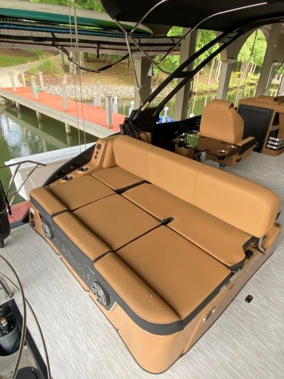 Slide: The Image of 2023 Harris FloteBote 250 Grand Mariner with tan seating, docked by a lakeside. - 8