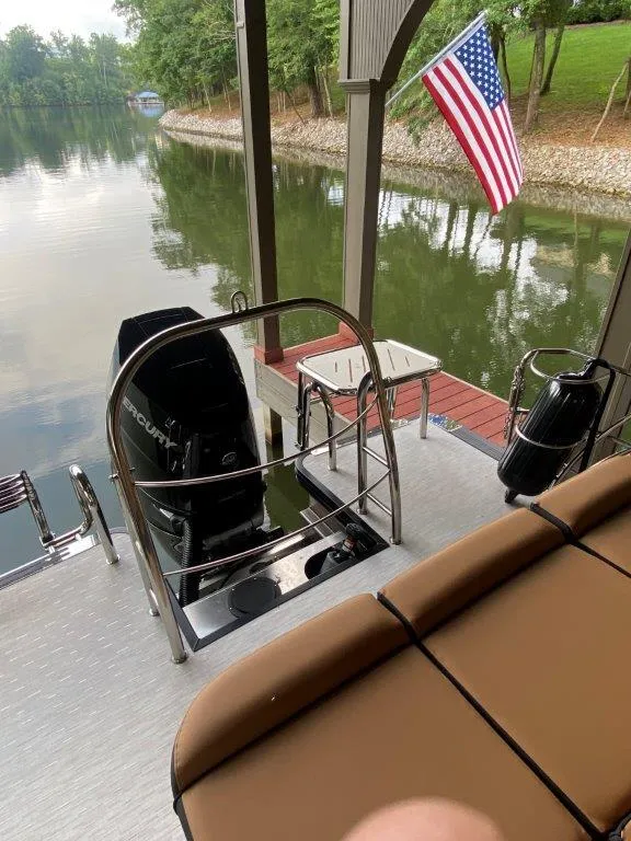 Slide: The Image of 2023 Harris FloteBote 250 Grand Mariner docked by a serene lake with American flag. - 9