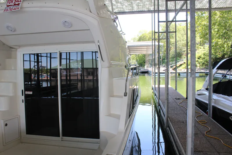 Slide: The Image of 2009 Carver 36SS yacht docked in a marina, featuring sliding glass doors and a For Sale sign. - 15