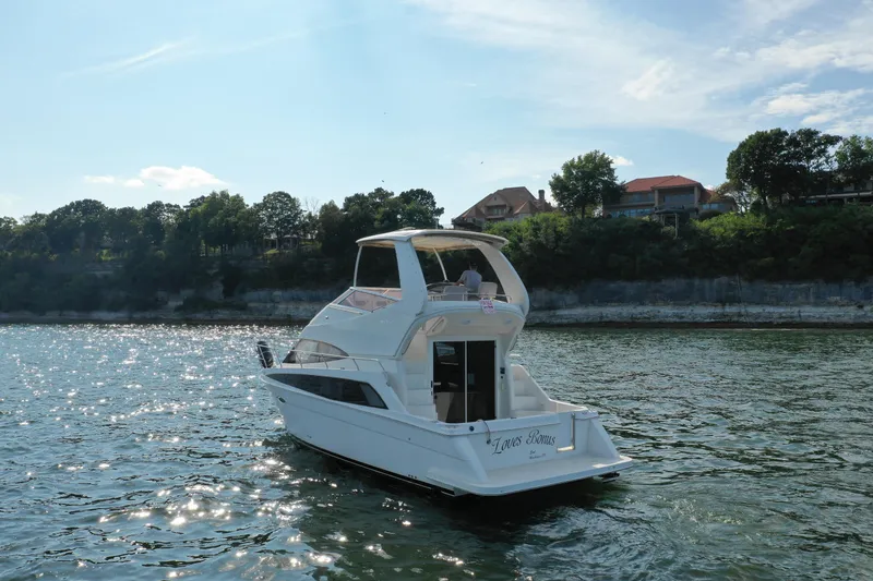 Slide: The Image of 2009 Carver 36SS yacht cruising on a sunny day near a scenic shoreline. - 5