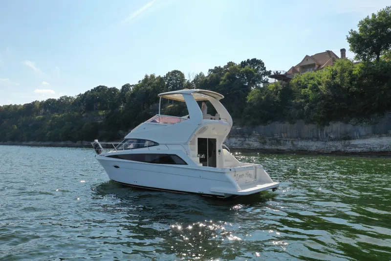 Slide: The Image of 2009 Carver 36SS yacht cruising on a scenic lake near a forested shoreline. - 7