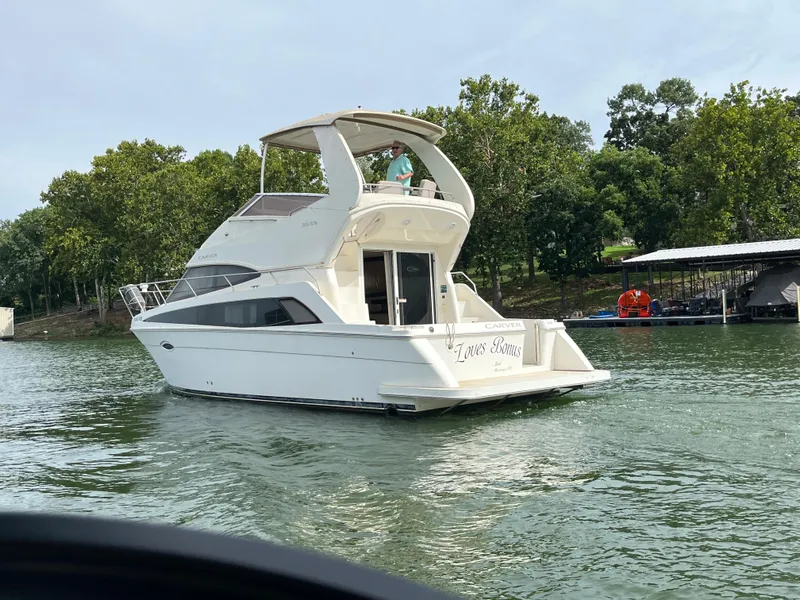 Slide: The Image of 2009 Carver 36SS yacht cruising on a lake near a dock and trees. - 9