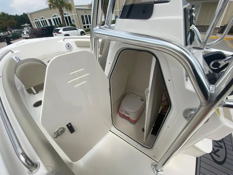 Slide: The Image of 2024 Key West 203 FS boat interior with open storage compartment and portable toilet. - 14