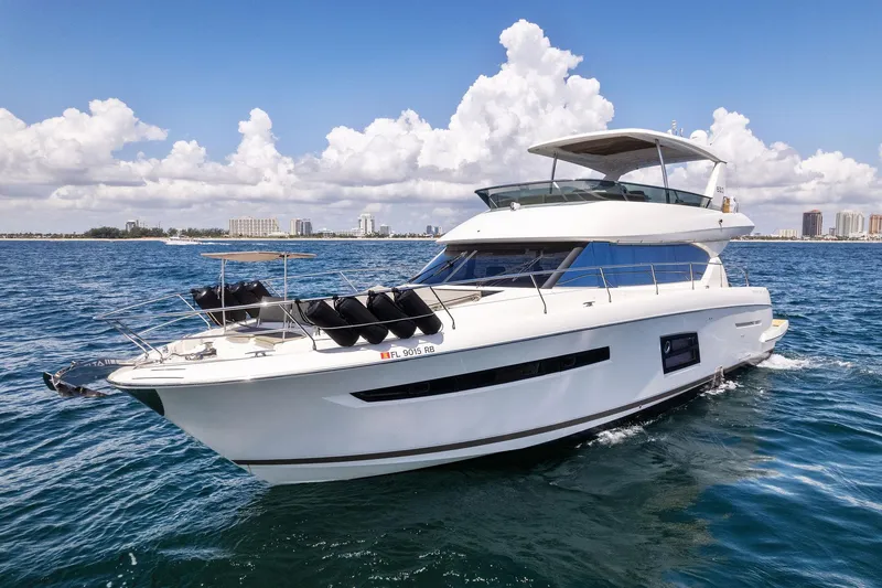 Slide: The Image of 2016 Prestige 620 yacht cruising on open water with city skyline in the background. - 2