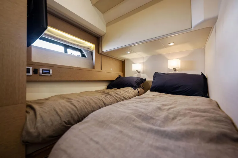 Slide: The Image of Prestige 620 2016 yacht cabin with twin beds, modern lighting, and window view. - 36