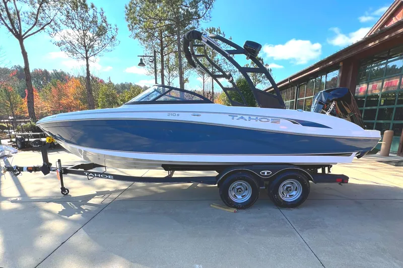 Slide: The Image of 2024 Tahoe 210 S boat on trailer, blue and white, outdoor display. - 0