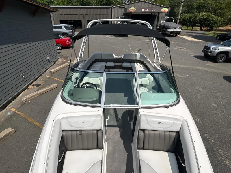 Slide: The Image of 2011 Regal 2500 Bowrider boat with black bimini top in parking lot. - 27