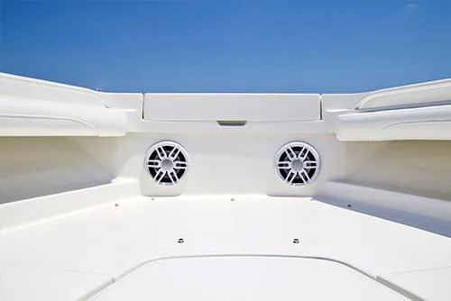 Slide: The Image of 2024 Regulator 23 boat interior with speakers and seating, white finish, blue sky background. - 11