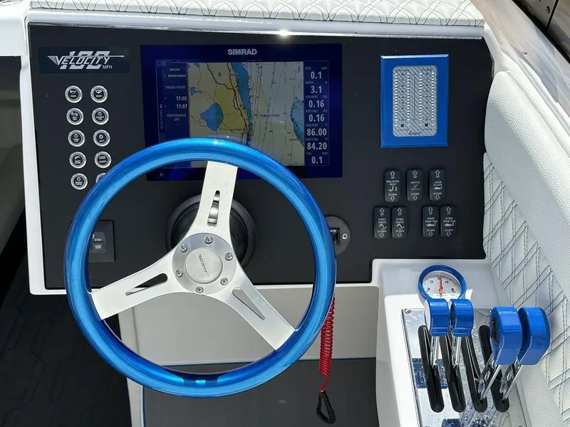 Slide: The Image of 2024 Velocity 290sc boat dashboard with blue steering wheel and navigation system. - 23