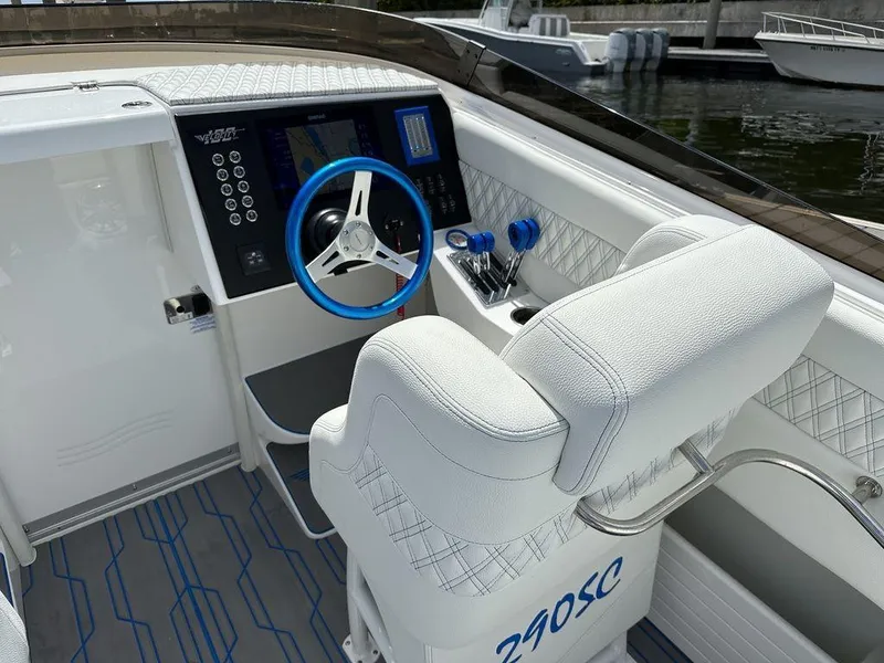 Slide: The Image of 2024 Velocity 290sc boat cockpit with white seating and blue steering wheel. - 6