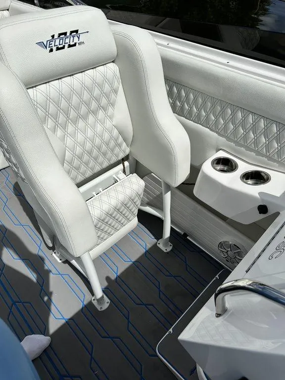 Slide: The Image of 2024 Velocity 290sc boat interior with white diamond-stitched seats and cup holders. - 7