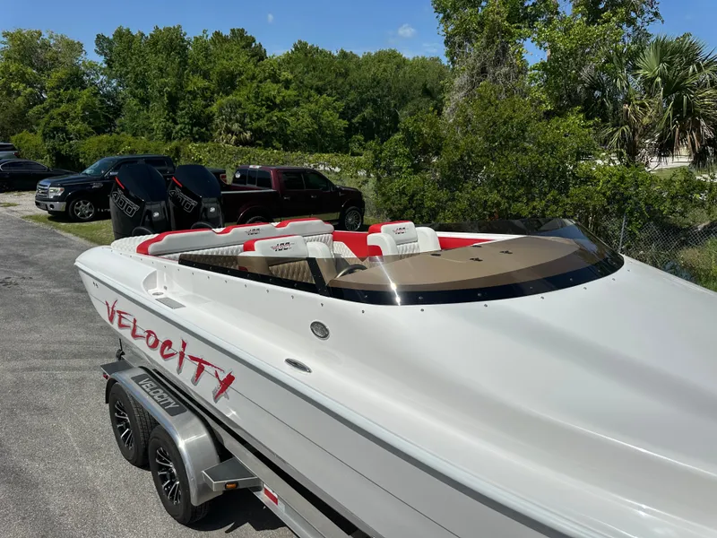 Slide: The Image of 2025 Velocity 290 SC speedboat on trailer, sleek design, white with red accents, parked outdoors. - 12