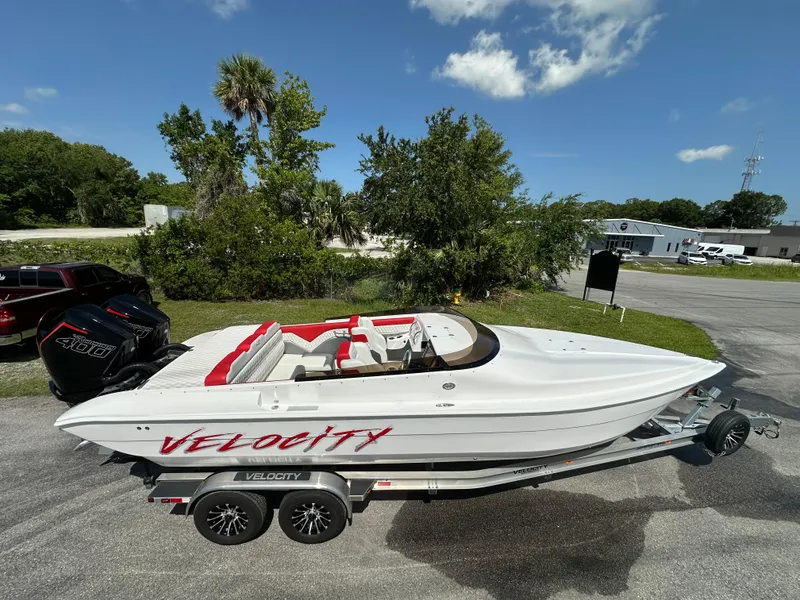 Slide: The Image of 2025 Velocity 290 SC speedboat on trailer, white with red accents, parked outdoors. - 13