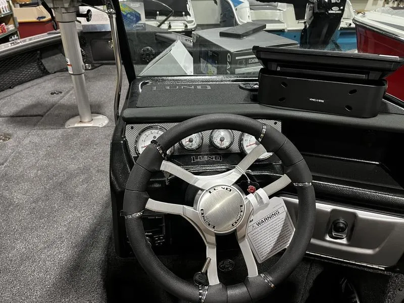 Slide: The Image of 2024 Lund 1875 Pro V Sport boat dashboard with steering wheel and instrument panel. - 9
