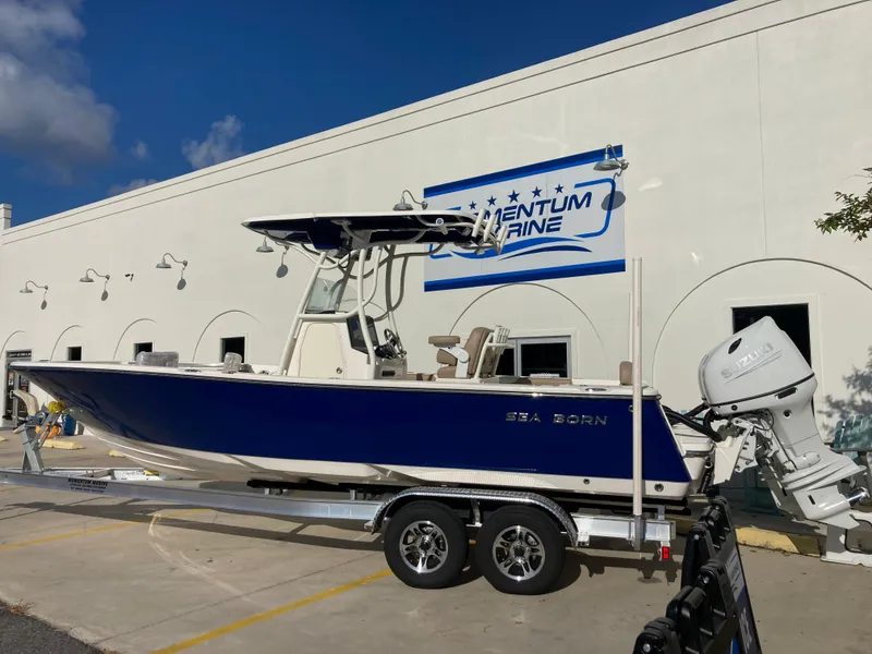 Slide: The Image of 2024 Sea Born LX24 boat on a trailer outside a marine dealership. - 2
