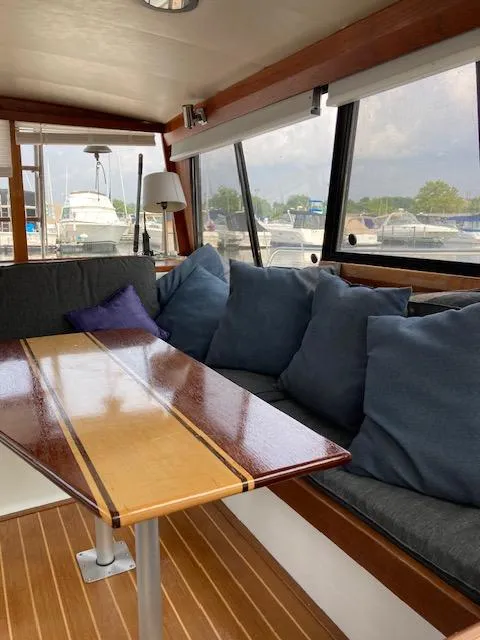 Slide: The Image of Interior of 1990 Bayliner 3288 Motoryacht with cushioned seating and wooden table. - 12