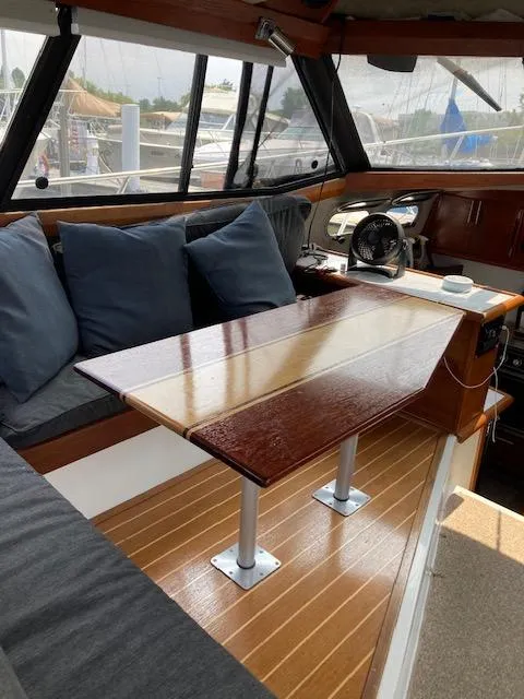Slide: The Image of Interior of a 1990 Bayliner 3288 Motoryacht with a wooden table and cushioned seating. - 3