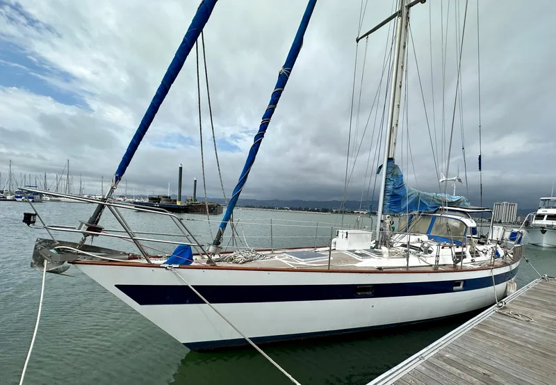 The Image of 1983 Norseman 447 CC Cutter sailboat docked in a marina under cloudy skies. - 0