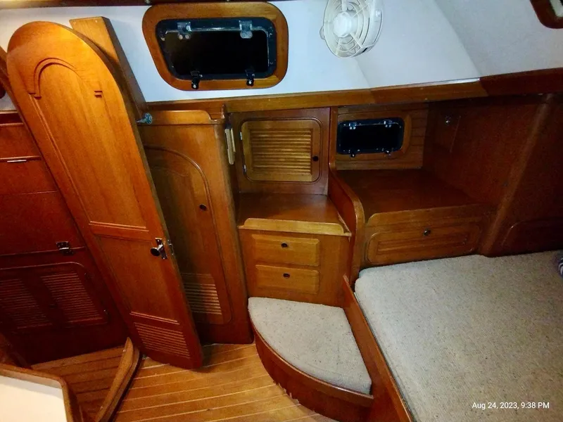 Slide: The Image of Interior of 1983 Norseman 447 CC Cutter, featuring wooden cabinetry and cozy seating area. - 15
