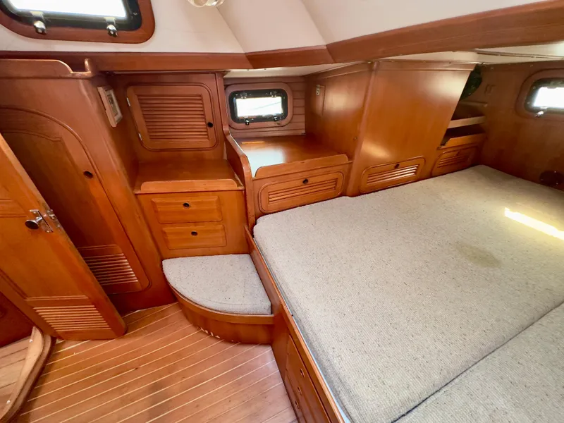 Slide: The Image of Interior of 1983 Norseman 447 CC Cutter, featuring wooden cabinetry and a cozy bed. - 16