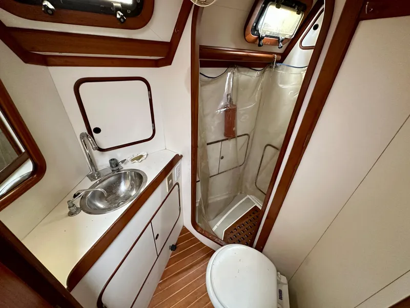 Slide: The Image of 1983 Norseman 447 CC Cutter bathroom with sink, shower, and toilet, featuring wood accents. - 18