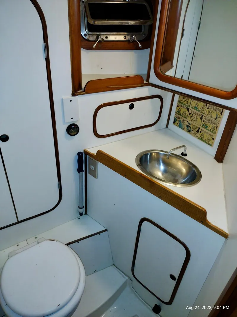 Slide: The Image of 1983 Norseman 447 CC Cutter bathroom with sink, toilet, and storage cabinets. - 19