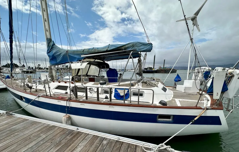 Slide: The Image of 1983 Norseman 447 CC Cutter sailboat docked at marina under cloudy sky. - 2