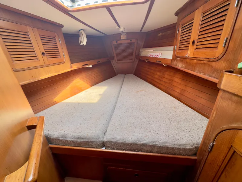 Slide: The Image of 1983 Norseman 447 CC Cutter cabin interior with wooden finish and cushioned bed. - 26