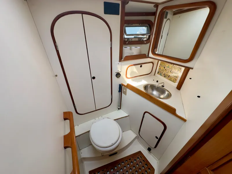 Slide: The Image of 1983 Norseman 447 CC Cutter bathroom with sink, toilet, mirror, and storage cabinets. - 27