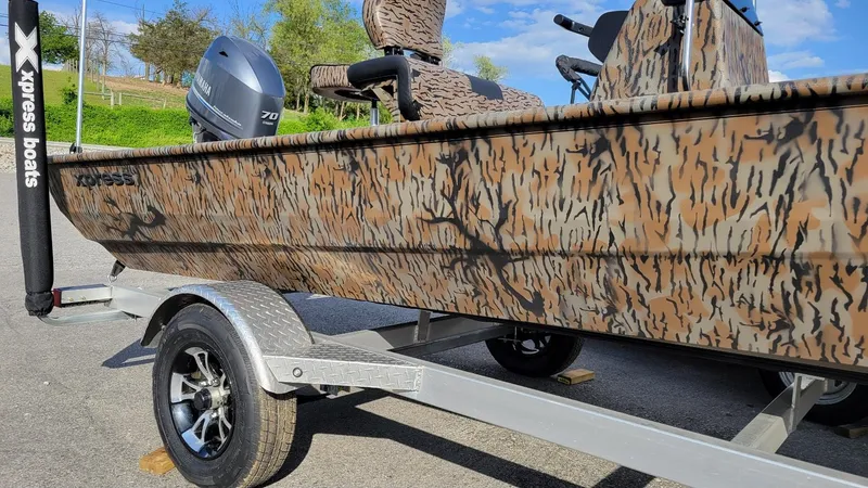 Slide: The Image of 2025 Xpress XP18CC boat with Yamaha 70 hp engine, camo design, on trailer. - 3