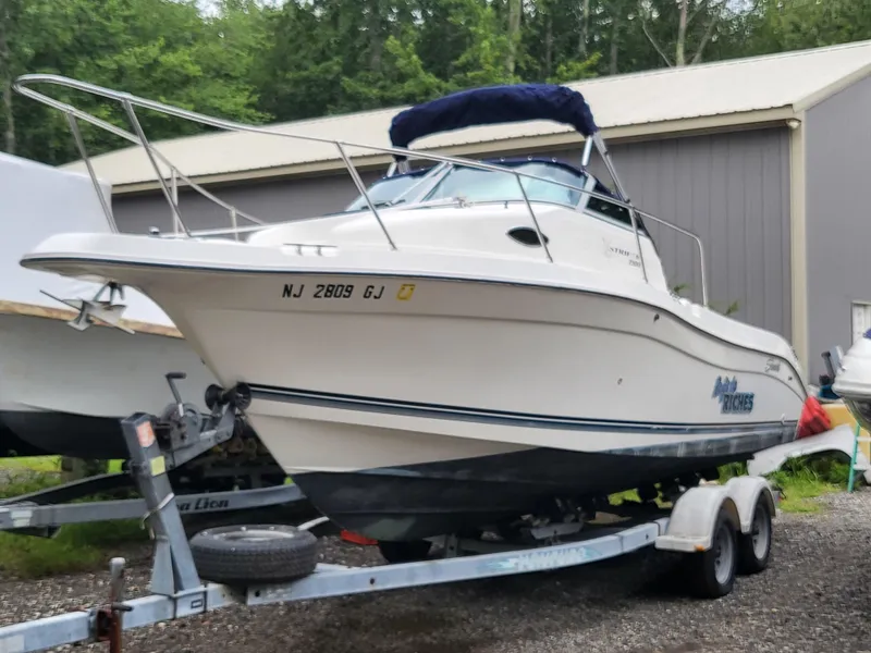 The Image of 1998 Seaswirl 2300 Walkaround boat on trailer, parked outdoors near a building. - 0