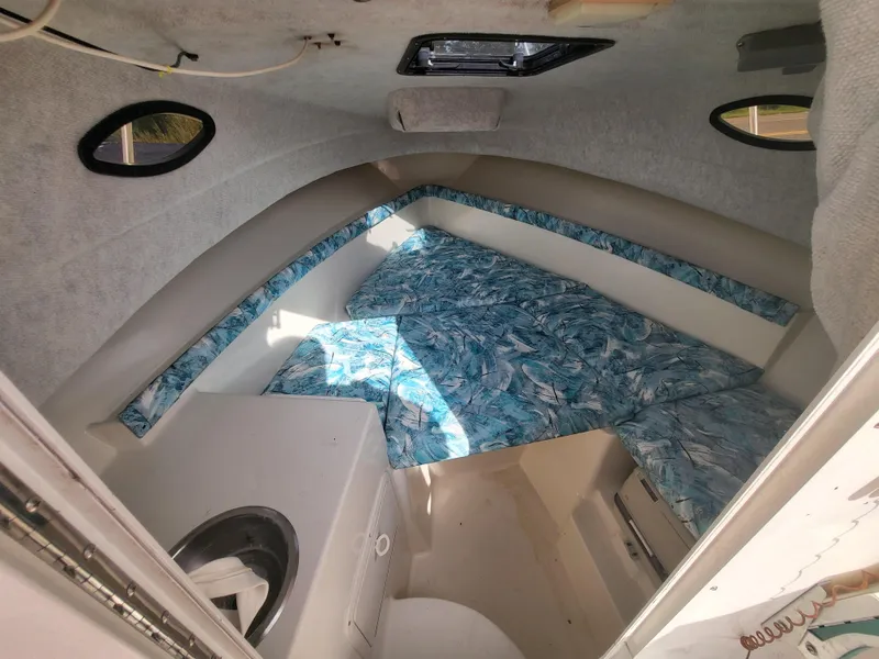 Slide: The Image of 1998 Seaswirl 2300 Walkaround cabin interior with patterned cushions and small windows. - 2