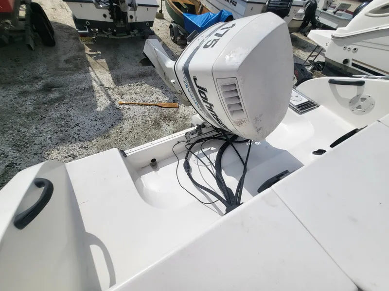 Slide: The Image of 1998 Seaswirl 2300 Walkaround boat with Johnson outboard motor, docked on gravel surface. - 22