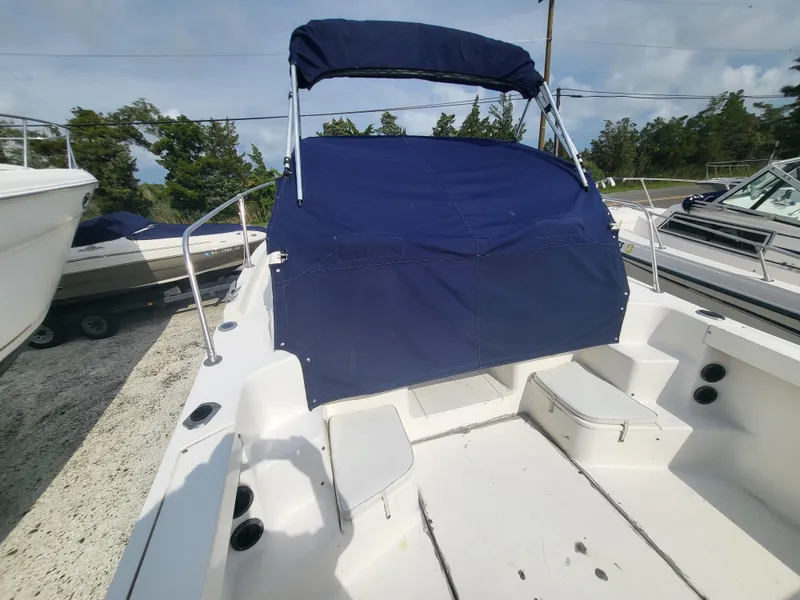 Slide: The Image of 1998 Seaswirl 2300 Walkaround boat with blue canopy, docked outdoors. - 23