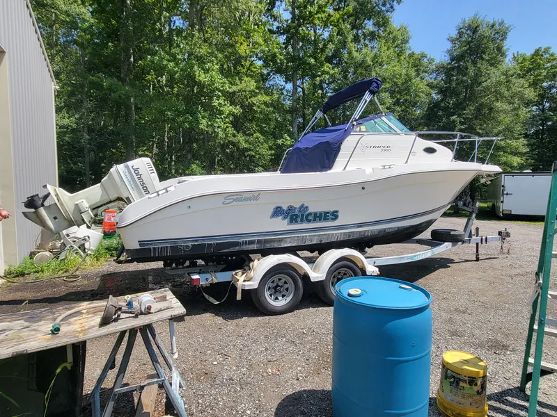 Slide: The Image of 1998 Seaswirl 2300 Walkaround boat on trailer, parked outdoors near trees. - 7