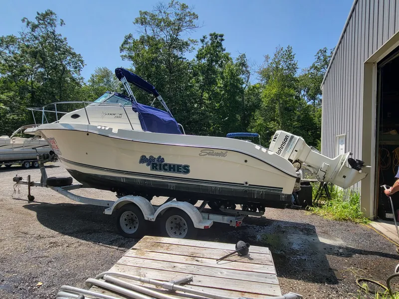 Slide: The Image of 1998 Seaswirl 2300 Walkaround boat on trailer, parked outdoors near trees and a building. - 9