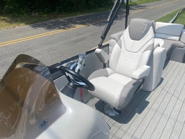 Slide: The Image of 2023 Avalon Catalina 2385 Quad Lounger boat interior with captain's chair and steering console. - 12
