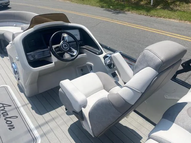 Slide: The Image of 2023 Avalon Catalina 2385 Quad Lounger boat interior with captain's chair and steering console. - 19