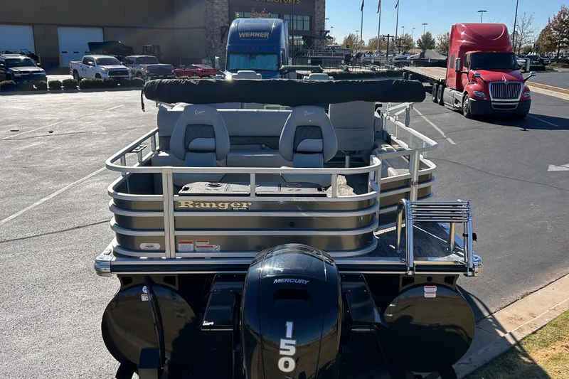 Slide: The Image of 2024 Ranger Reata 223F pontoon boat with Mercury 150 engine in a parking lot. - 2