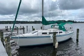 Slide: The Image of 1986 Laguna 30 sailboat docked on a cloudy day, featuring green sail covers. - 21