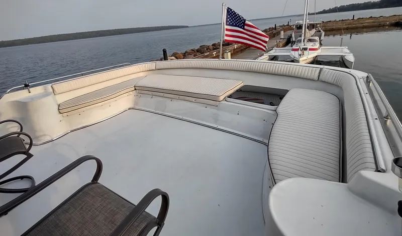 Slide: The Image of 1991 Bluewater Coastal Cruiser boat deck with seating, American flag, and waterfront view. - 11