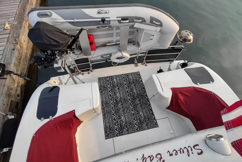 Slide: The Image of 1991 Bluewater Coastal Cruiser with red seating and attached inflatable boat at dock. - 13