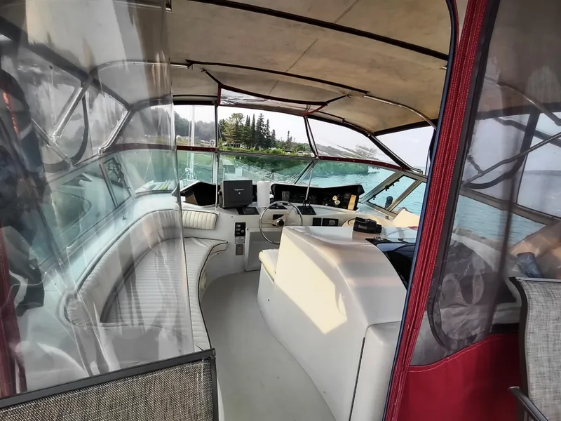 Slide: The Image of 1991 Bluewater Coastal Cruiser interior with helm, overlooking serene waters and distant trees. - 14