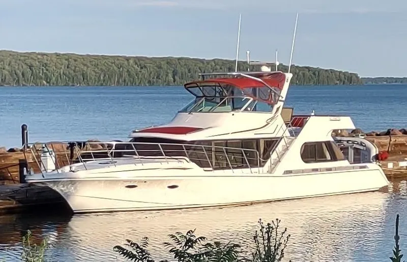 Slide: The Image of 1991 Bluewater Coastal Cruiser yacht docked by a serene lake with lush forest backdrop. - 2