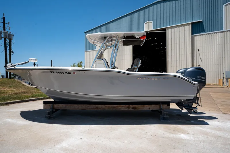 Slide: The Image of 2021 Key West 244 Center Console boat on trailer near a large warehouse. - 0