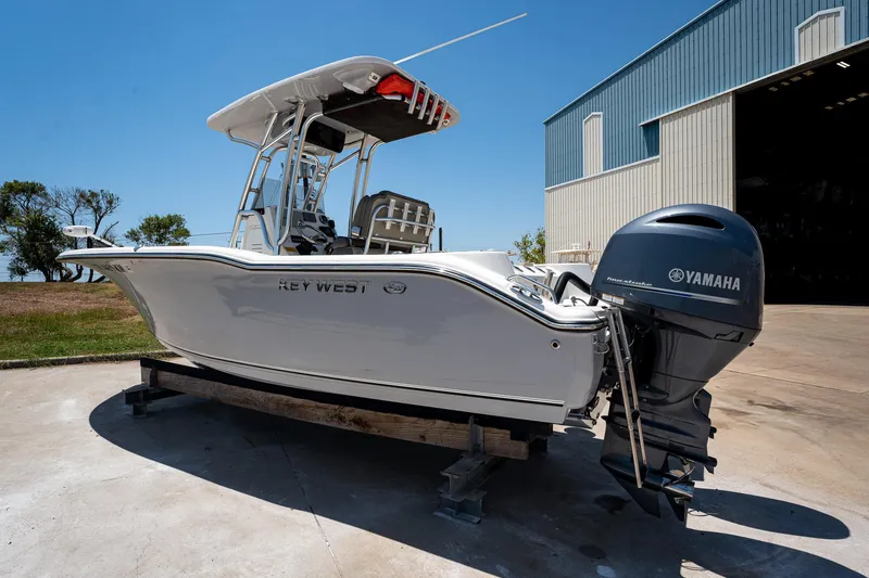 Slide: The Image of 2021 Key West 244 Center Console boat with Yamaha engine, parked outside a warehouse. - 4