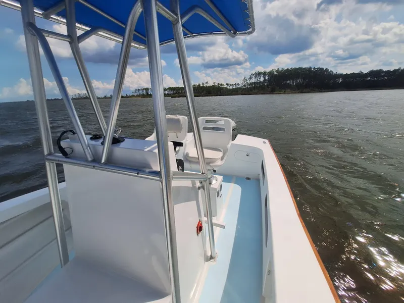 Slide: The Image of 2008 Custom Carolina boat on water with blue canopy and scenic shoreline. - 18